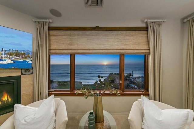 dining room with a warm lit fireplace, a water view, baseboards, and visible vents