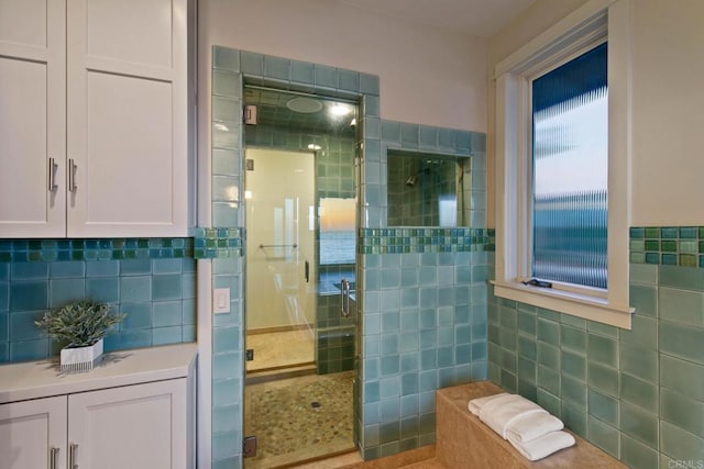 full bathroom with tile walls, tasteful backsplash, and a shower stall