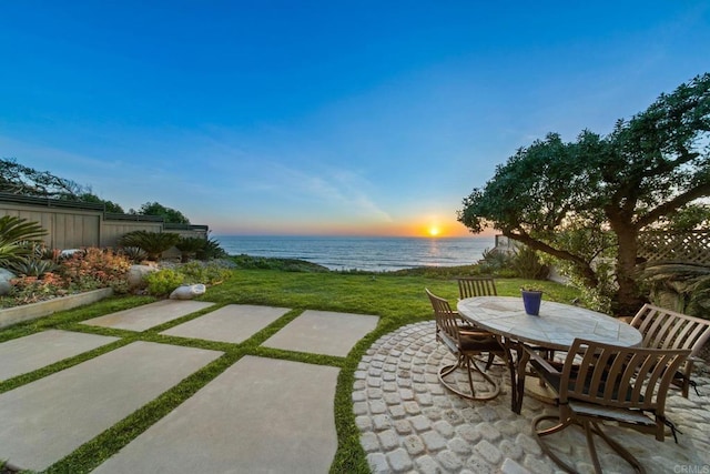 patio terrace at dusk with a water view and outdoor dining space