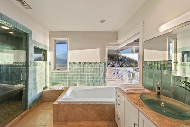 full bathroom with tile walls, a stall shower, a garden tub, and visible vents
