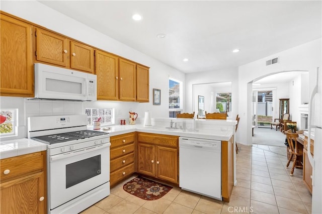 5775 Myrtle Beach Dr, Banning, CA 92220 - kitchen with white appliances, a peninsula, arched walkways, tile counters, and light tile patterned floors