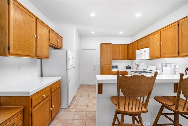 5775 Myrtle Beach Dr, Banning, CA 92220 - kitchen featuring white appliances, a peninsula, a kitchen breakfast bar, light tile patterned floors, and recessed lighting