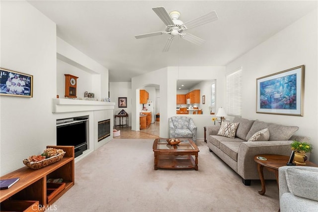 5775 Myrtle Beach Dr, Banning, CA 92220 - living area featuring ceiling fan, arched walkways, a glass covered fireplace, and light colored carpet