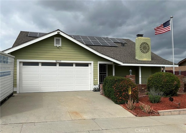 view of front of home featuring roof with shingles, solar panels, concrete driveway, covered porch, and a garage