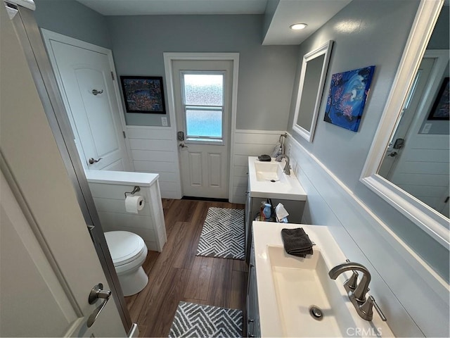 bathroom with wainscoting, wood finished floors, vanity, and toilet