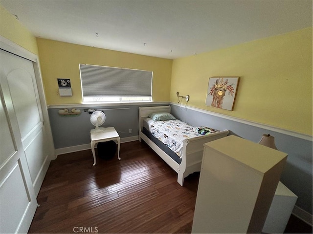 bedroom with wood finished floors, a closet, and baseboards