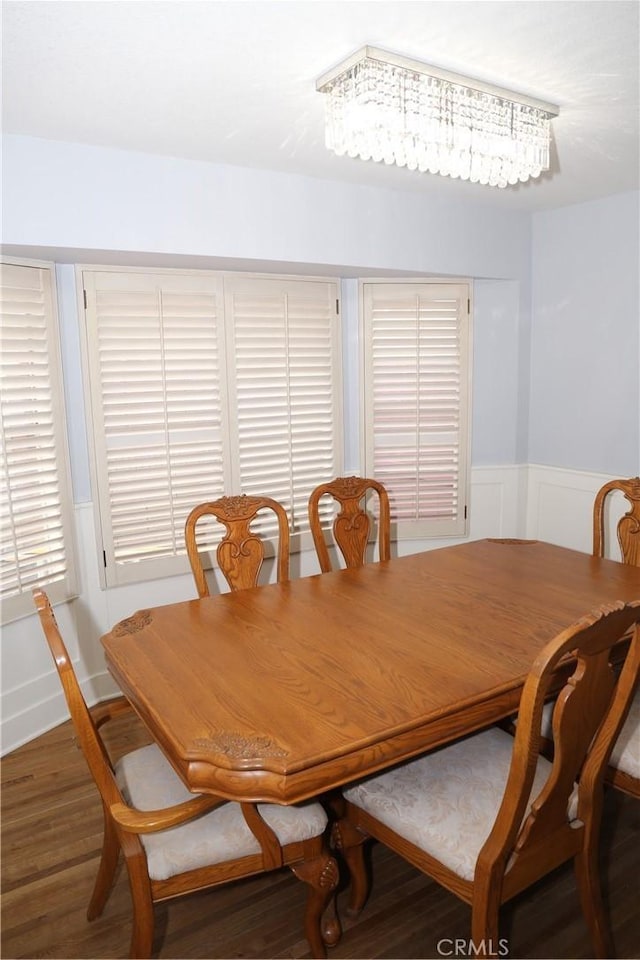 dining area featuring wainscoting, wood finished floors, and a decorative wall