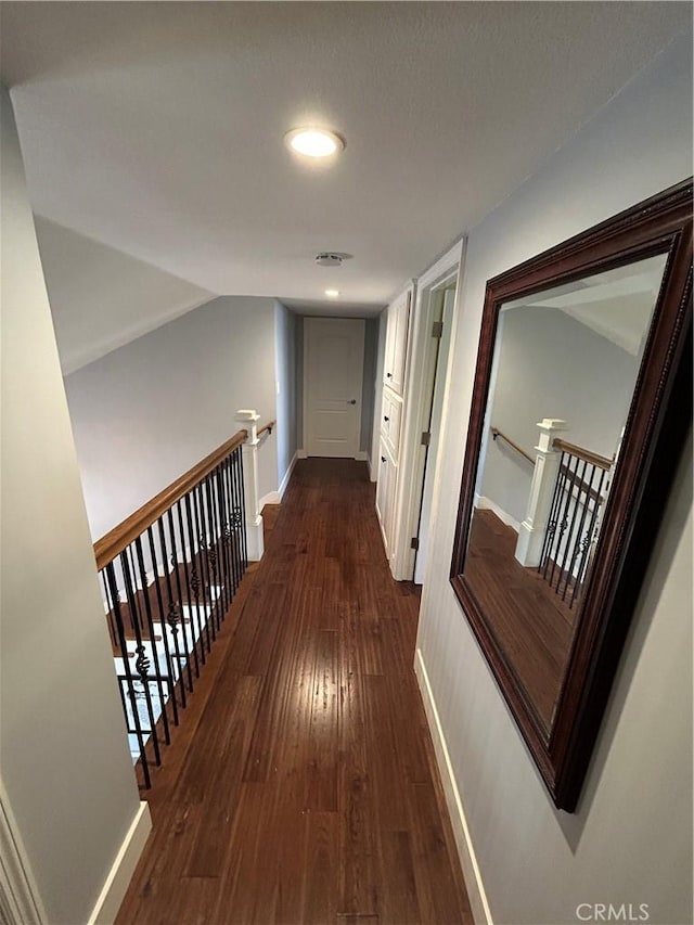 corridor with vaulted ceiling, baseboards, dark wood-style flooring, and an upstairs landing