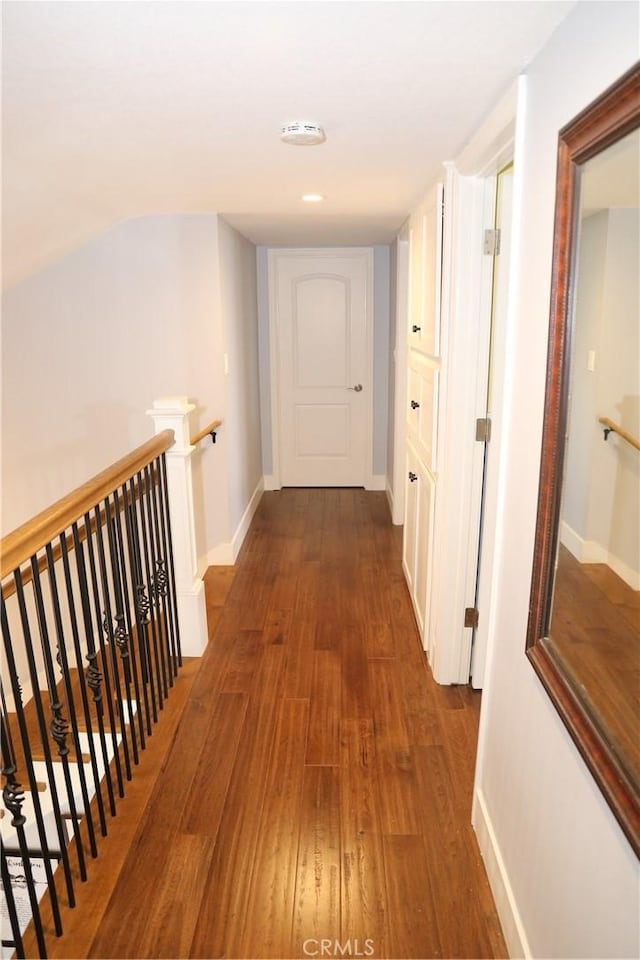 corridor featuring an upstairs landing, baseboards, and wood finished floors