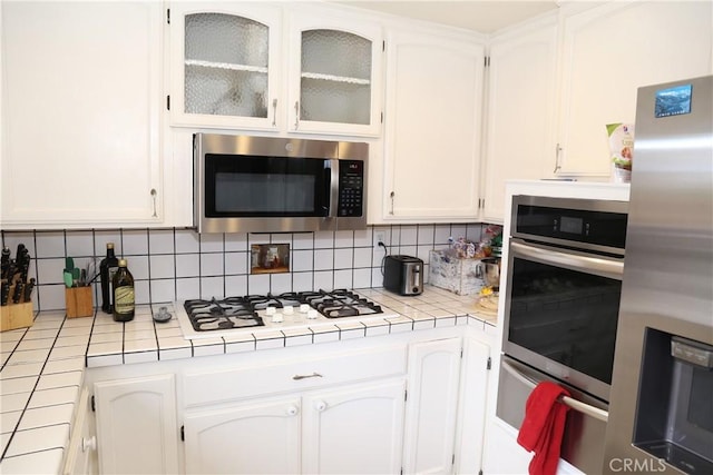 kitchen with tile counters, white cabinetry, and appliances with stainless steel finishes