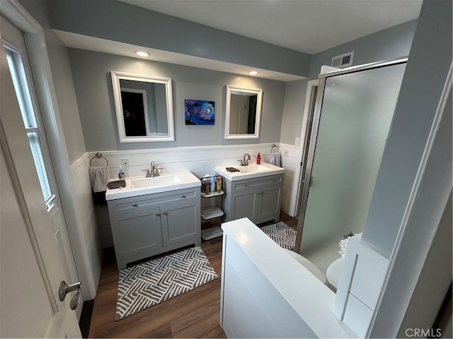 bathroom featuring visible vents, wood finished floors, a sink, and a shower stall