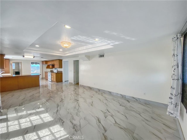 13827 Olathe Rd, Apple Valley, CA 92307 - unfurnished living room with a tray ceiling, light marble finish flooring, and recessed lighting