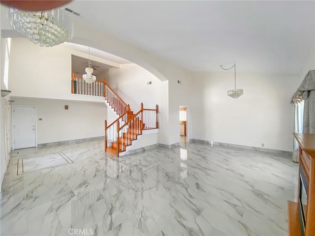 13827 Olathe Rd, Apple Valley, CA 92307 - unfurnished living room featuring a chandelier, stairs, arched walkways, marble finish floors, and baseboards