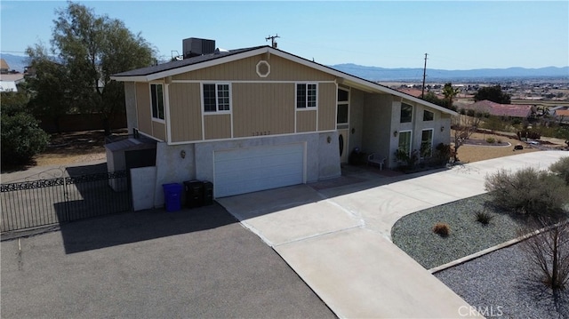 13827 Olathe Rd, Apple Valley, CA 92307 - view of front of property featuring asphalt driveway, cooling unit, an attached garage, a mountain view, and fence