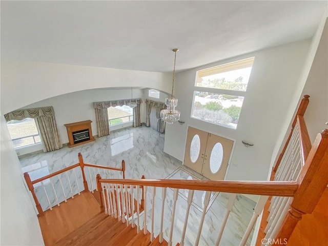 13827 Olathe Rd, Apple Valley, CA 92307 - stairs featuring a chandelier, wood finished floors, arched walkways, and a high ceiling