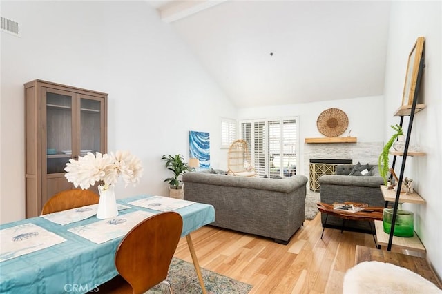 310 Lake St Unit 216, Huntington Beach, CA 92648 - living room featuring high vaulted ceiling, visible vents, light wood-style flooring, beamed ceiling, and a fireplace