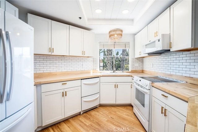 310 Lake St Unit 216, Huntington Beach, CA 92648 - kitchen with white appliances, wooden counters, a sink, light wood-type flooring, and a tray ceiling