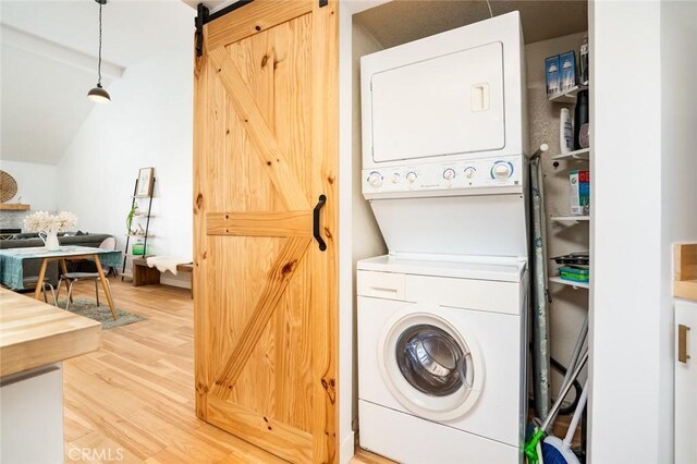 310 Lake St Unit 216, Huntington Beach, CA 92648 - clothes washing area with stacked washer / dryer, a barn door, laundry area, and wood finished floors