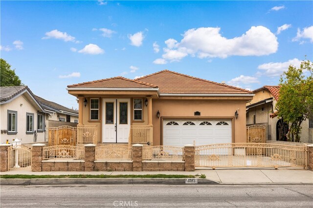 single story home with a fenced front yard, a gate, driveway, an attached garage, and stucco siding