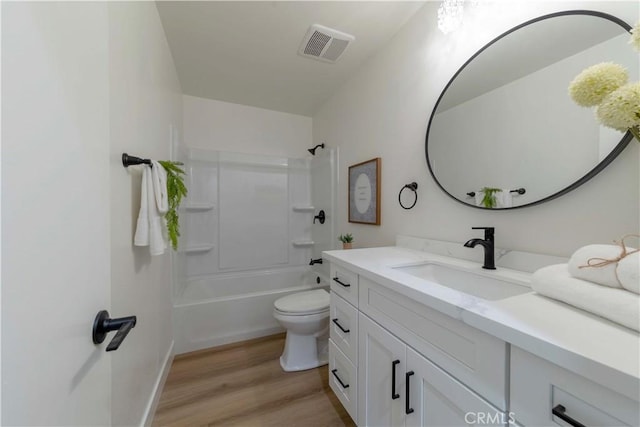 bathroom featuring toilet, vanity, wood finished floors, visible vents, and shower / bath combination