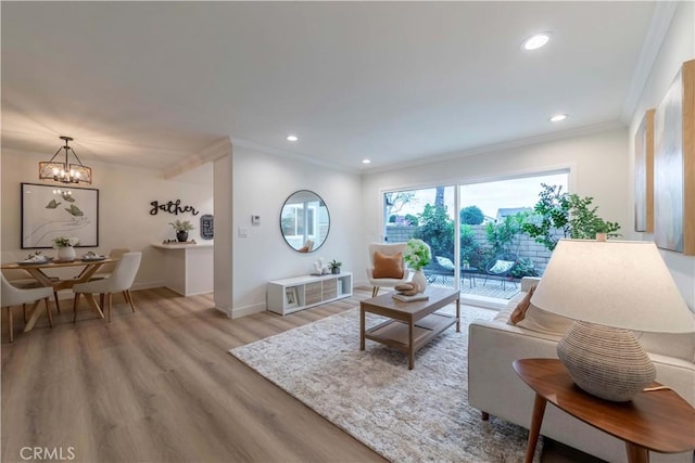 living area featuring crown molding, recessed lighting, an inviting chandelier, baseboards, and light wood-style flooring