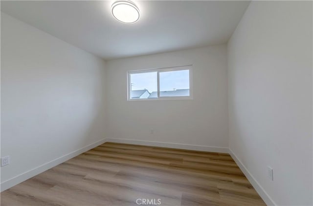 spare room featuring baseboards and light wood finished floors