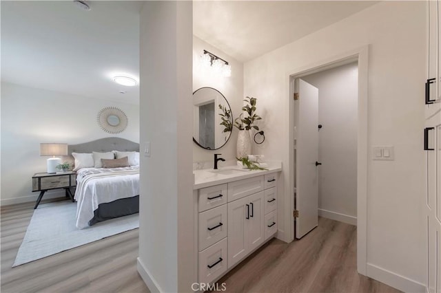 ensuite bathroom featuring vanity, ensuite bath, baseboards, and wood finished floors