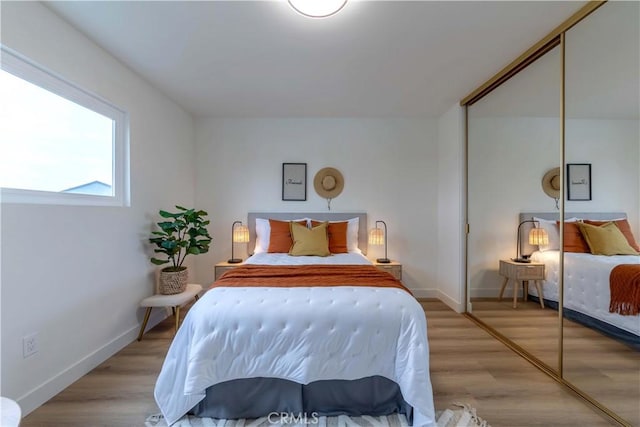 bedroom with baseboards, a closet, and light wood-type flooring