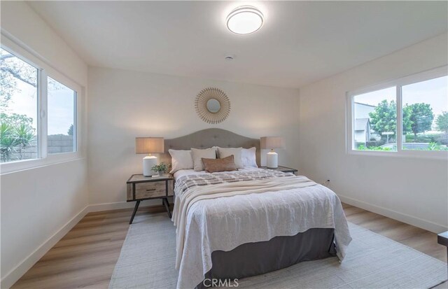 bedroom featuring light wood finished floors and baseboards