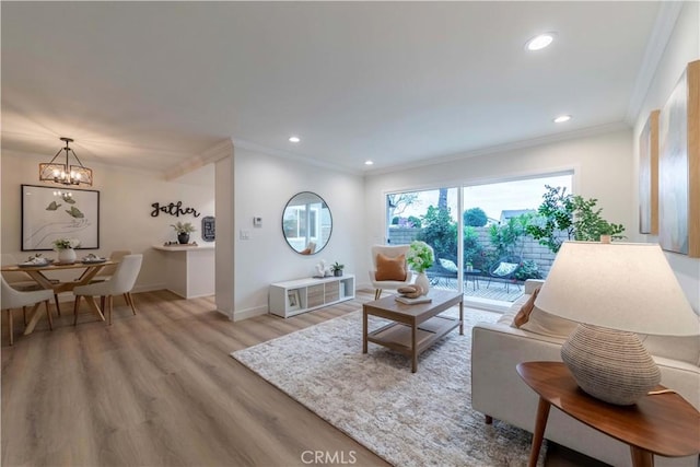 living room with recessed lighting, ornamental molding, baseboards, light wood-style flooring, and a notable chandelier