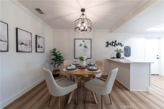 dining space featuring a chandelier, light wood-type flooring, baseboards, visible vents, and ornamental molding