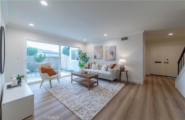 living room with visible vents, light wood-style floors, ornamental molding, and recessed lighting
