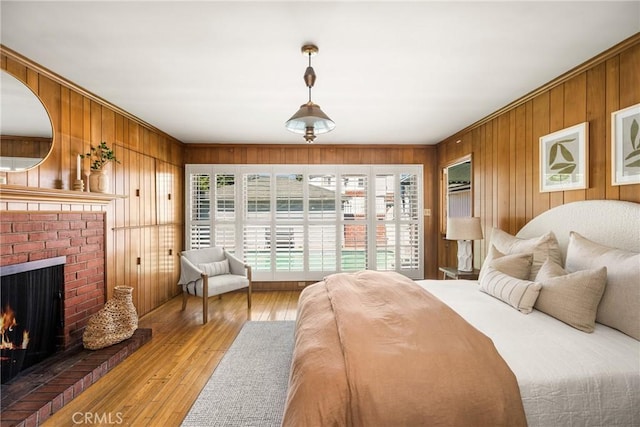 bedroom with wooden walls, a brick fireplace, and wood-type flooring