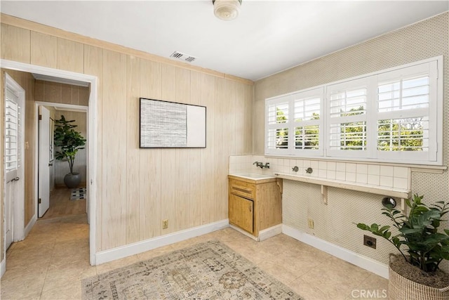 interior space featuring light tile patterned floors, a sink, baseboards, and visible vents