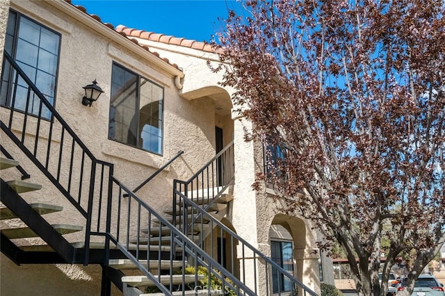 view of side of property featuring a tiled roof, stairs, and stucco siding