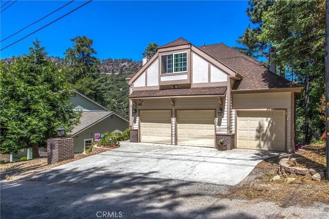6180 Cedar Ave, Angelus Oaks, CA 92305 - view of front facade with brick siding, driveway, roof with shingles, and a garage