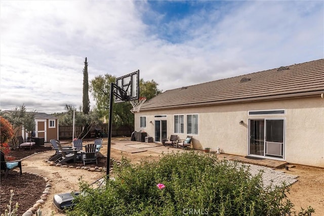 back of house with a shed, an outdoor structure, a tiled roof, and stucco siding