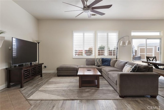 living area featuring baseboards, visible vents, wood finished floors, and ceiling fan