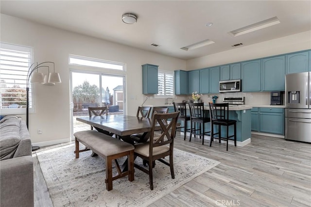 dining room featuring baseboards, light wood-type flooring, and visible vents