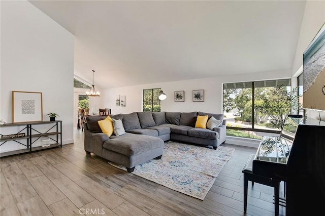 living room with a chandelier, wood finished floors, and high vaulted ceiling