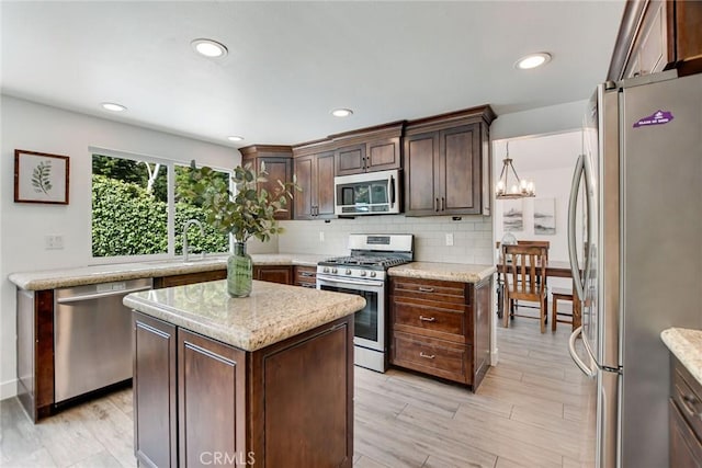 kitchen with stainless steel appliances, decorative backsplash, a sink, light wood finished floors, and recessed lighting
