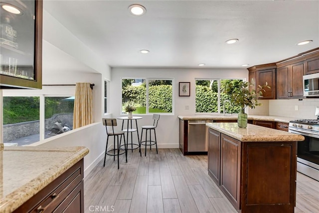 kitchen with appliances with stainless steel finishes, recessed lighting, light stone countertops, baseboards, and dark brown cabinetry
