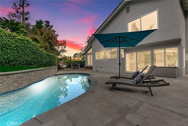 pool at dusk featuring a patio area