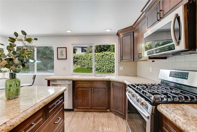 kitchen with appliances with stainless steel finishes, tasteful backsplash, dark brown cabinetry, a sink, and recessed lighting