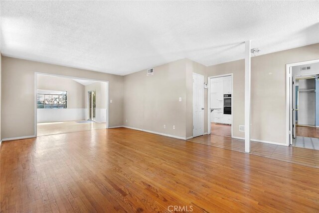 21032 Baltar St, Canoga Park, CA 91304 - unfurnished living room featuring hardwood / wood-style floors, baseboards, a textured ceiling, and visible vents