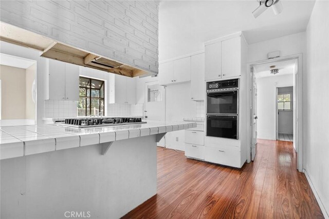 21032 Baltar St, Canoga Park, CA 91304 - kitchen with stainless steel gas cooktop, backsplash, dobule oven black, wood finished floors, and tile countertops
