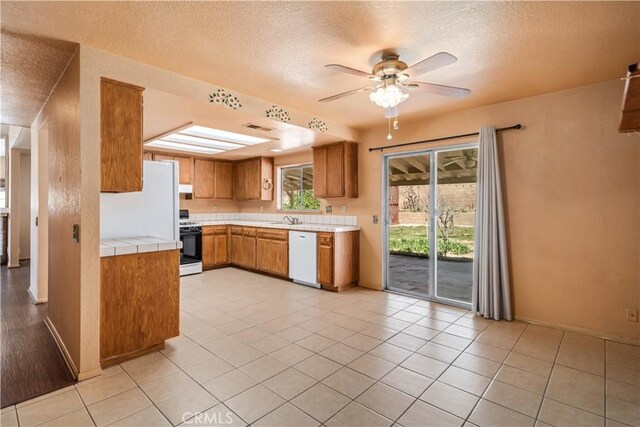 14935 Elizabeth Lake Rd, Lake Elizabeth, CA 93532 - kitchen with tile counters, white appliances, visible vents, a ceiling fan, and brown cabinetry