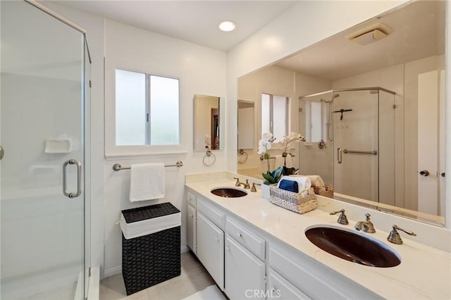 full bath featuring double vanity, visible vents, a sink, and a stall shower