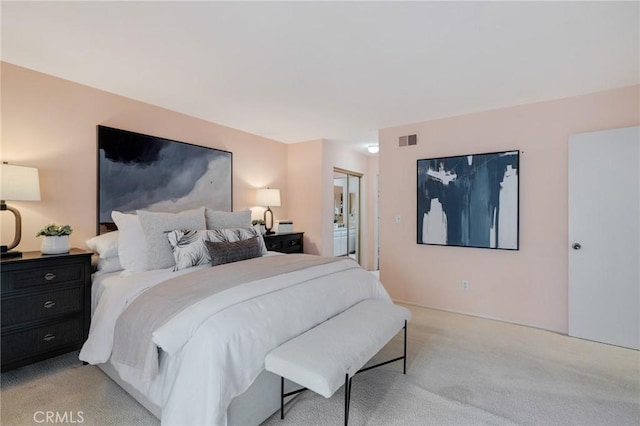 bedroom with light colored carpet, ensuite bathroom, and visible vents