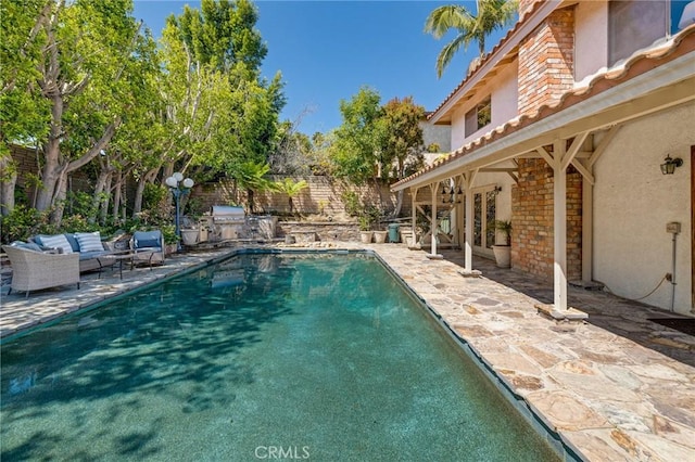 view of swimming pool with an outdoor kitchen, an outdoor living space, a grill, a patio area, and fence
